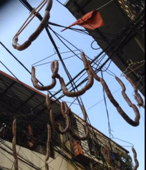 Tại khu vực ngõ 58, đường Hoàng Hoa Thám,người chế biến móc từng khúc lạp xưởng vào móc áo rồi đem treo trên...dây điện để phơi khô.