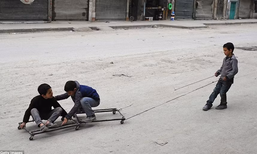 Những đứa trẻ Syria chơi đùa trên đường phố ở khu dân cư Shaar sau khi trận bão cát quét qua.