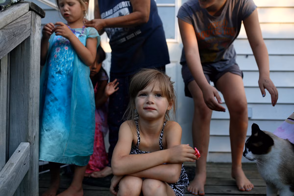 Nhiếp ảnh gia Stephanie Foden chụp cô bé Lila Chosa ngồi ở bậc thềm trước nhà trong khi người thân và bạn bè của Lila đứng phía sau sửa soạn để chụp ảnh. Được biết, bà của Lila Heart Warrior đã đấu tranh nhiều năm để giành quyền nuôi cháu gái ở Minnesota. (Nguồn ảnh: The Atlantic)