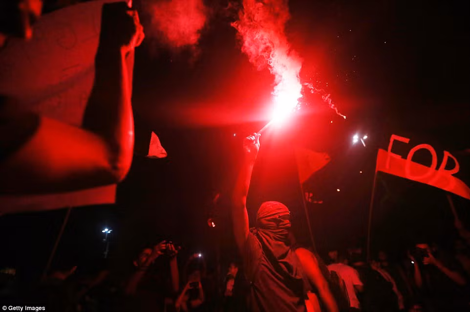 Một người biểu tình đeo mặt nạ đốt pháo sáng trong cuộc biểu tình phản đối dự luật cải cách của chính phủ liên bang ở thành phố Rio de Janeiro.