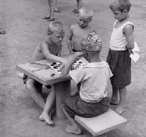 Hai bé trai mải mê chơi đánh cờ.