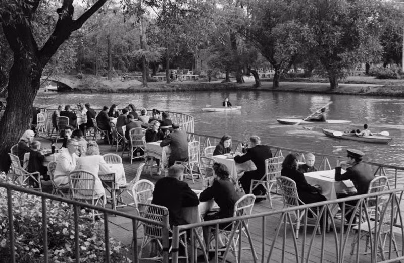 Mọi người ngồi ăn uống, trò chuyện bên bờ hồ.