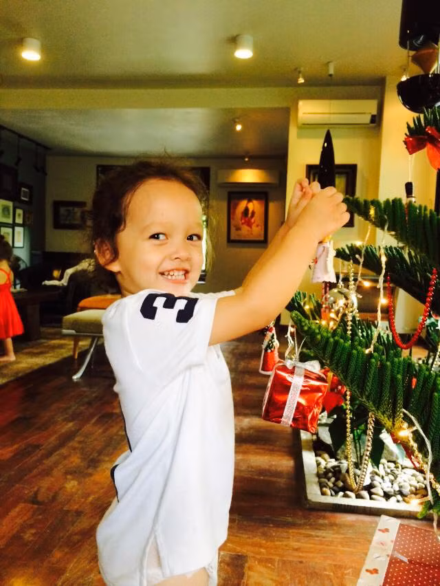 Bé Tôm tự tay trang trí cây thông trong nhà.