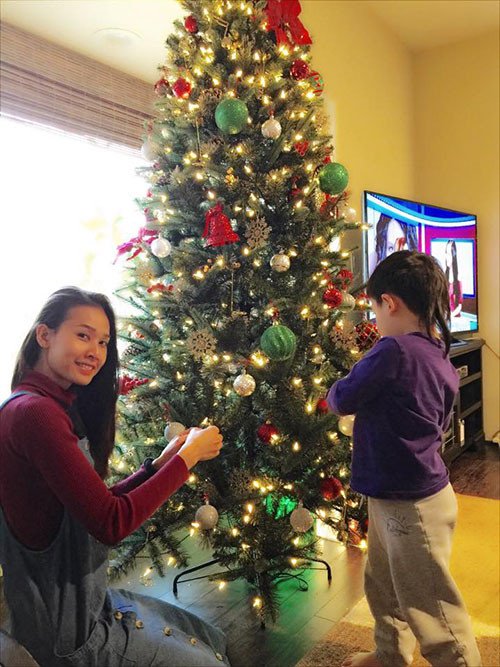 Cậu bé tỉ mẩn treo từng món đồ trang trí cây thông với người yêu của bố là Dương Mỹ Linh.