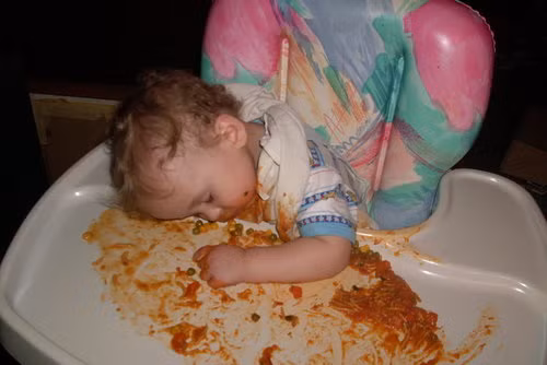 Em bé "quá mệt" ngủ gật trên bàn ăn sau khi biến nó thành bãi chiến trường.