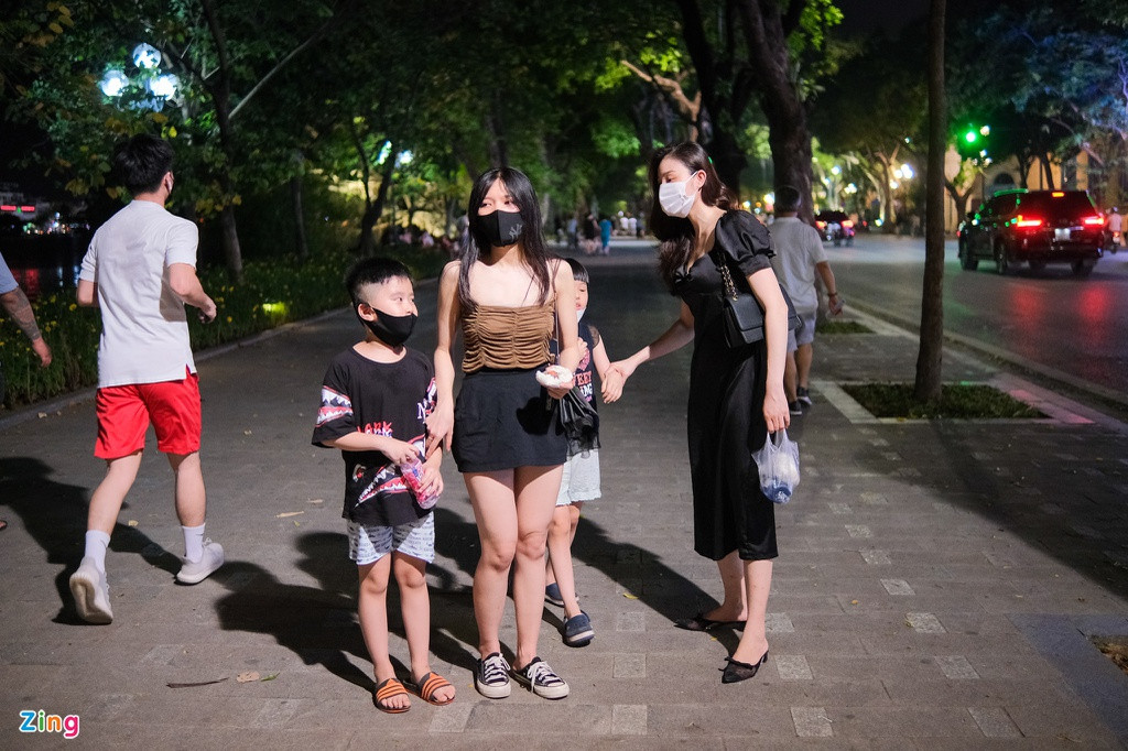 Minh Hằng (28 tuổi, trái), một giáo viên mầm non, cảm thấy tối 21/6 đã bớt oi bức hơn những ngày nắng vừa qua. Vì vậy, cô cùng một người bạn bạn quyết định đưa các con lên hồ Hoàn Kiếm tản bộ, hóng gió sau quãng thời gian dài ở nhà với điều hòa.