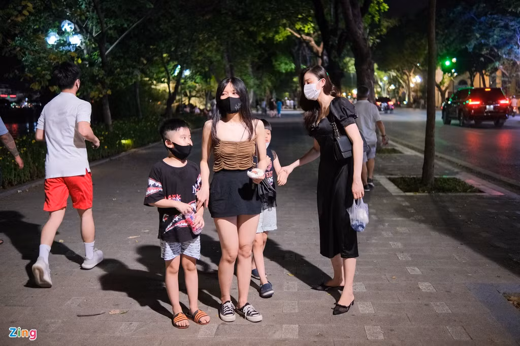 Minh Hằng (28 tuổi, trái), một giáo viên mầm non, cảm thấy tối 21/6 đã bớt oi bức hơn những ngày nắng vừa qua. Vì vậy, cô cùng một người bạn bạn quyết định đưa các con lên hồ Hoàn Kiếm tản bộ, hóng gió sau quãng thời gian dài ở nhà với điều hòa.