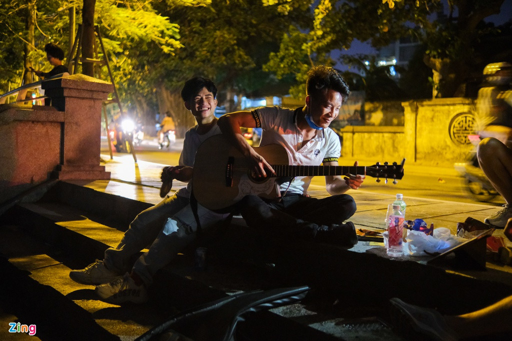 Tại bậc cầu thang dẫn xuống hồ Tây ở đoạn phố Vệ Hồ, một nhóm 4 nam thanh niên trẻ tuổi cùng nhau ngồi đàn hát và đón những cơn gió nóng mùa hè thổi từ phía mặt nước.