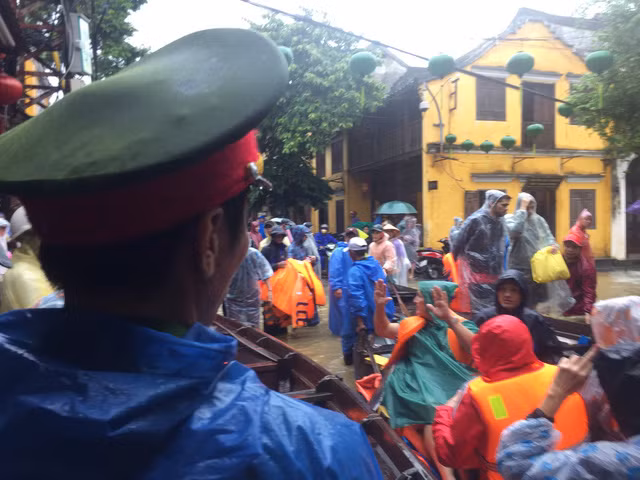 Khách du lịch cùng người dân di chuyển đồ đạc tại các khu lưu trú bị ngập úng ra nơi an toàn. Nguồn ảnh: Tuổi Trẻ