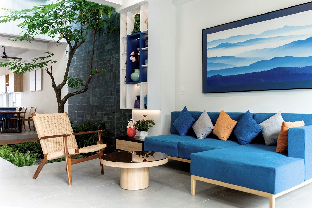 Phòng khách vừa có ánh sáng tự nhiên từ sân trước và ánh sáng từ giếng trời, cùng với nội thất màu xanh lam thẫm, là màu sắc ưa thích của gia chủ. 