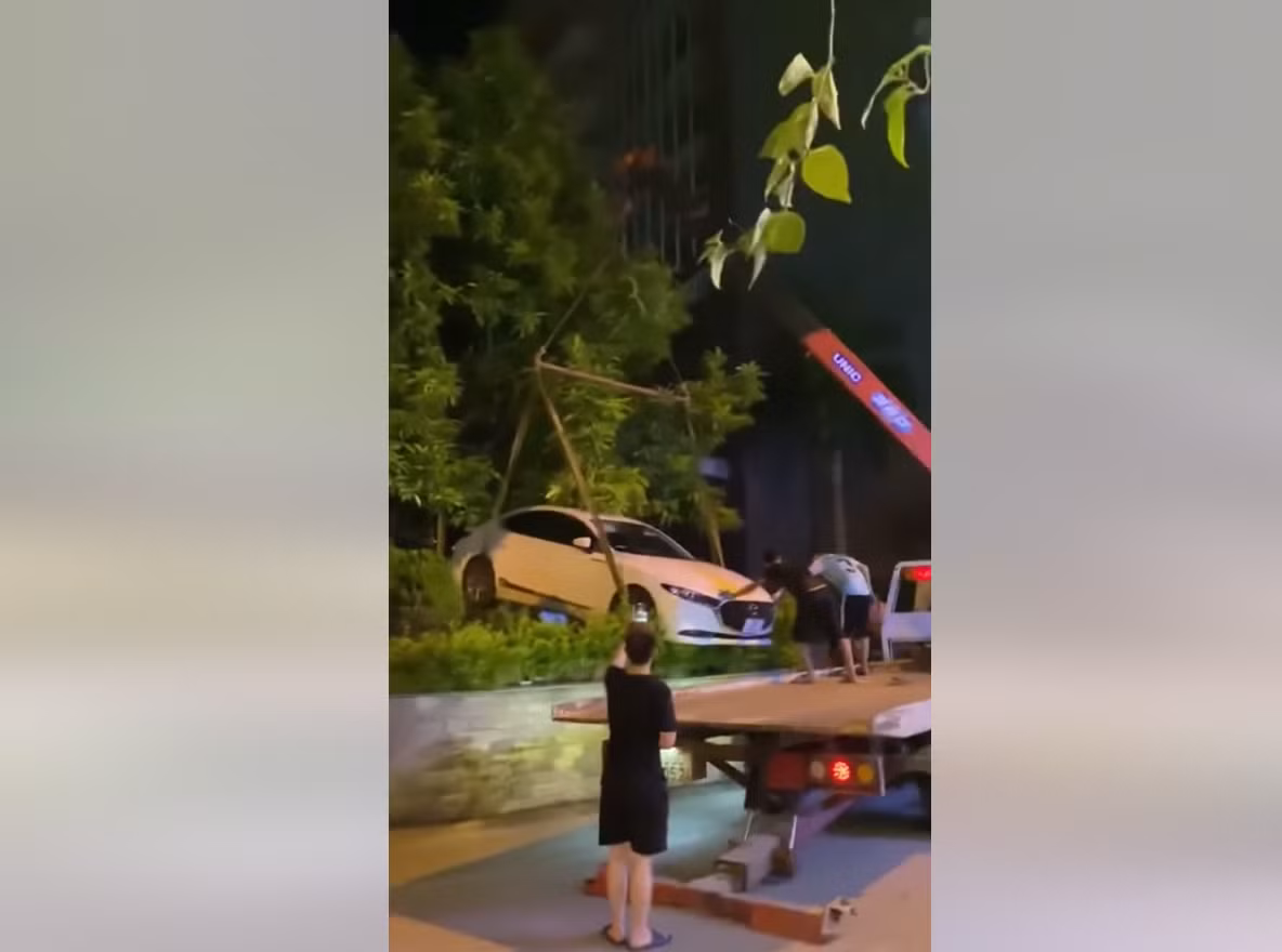 Người này cho biết, do chiếc xe ô tô Mazda 3 này đỗ xe không đúng quy định, chắn trước cửa nhà, chắn lối ra vào nên chủ nhà đã gọi xe cẩu đến nâng chiếc xe này giấu vào bụi cây. Ảnh: Cắt ra từ clip
