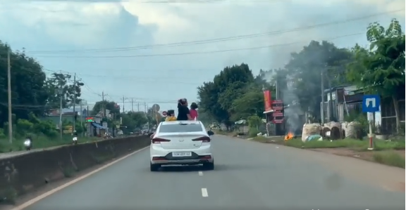 Theo clip, trên đường quốc lộ có dải phân cách cứng phân chia làn đường, một chiếc xe ô tô 5 chỗ màu trắng di chuyển trên đường và mở cửa sổ trời.