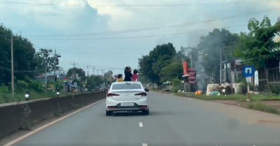 Điều đáng nói là có 3 đứa trẻ đã đứng nhoài hẳn người ra khỏi nóc xe, thoải mái chơi đùa ngắm cảnh xung quanh trong khi chiếc xe vẫn đang di chuyển.