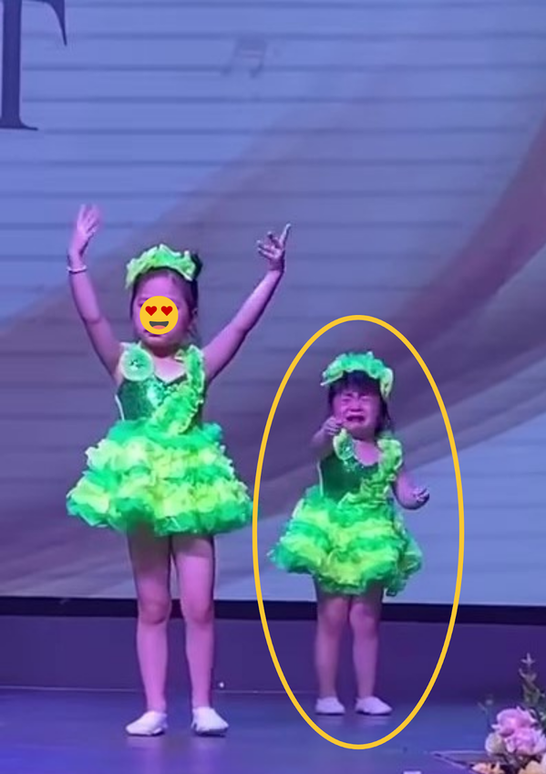 Cụ thể, trong đoạn video được mẹ cô bé đáng yêu này chia sẻ, có thể thấy cô bé đang mặc trang phục biểu diễn màu xanh, đầu đeo chiếc nơ xinh xắn. Ảnh: Cắt ra từ clip