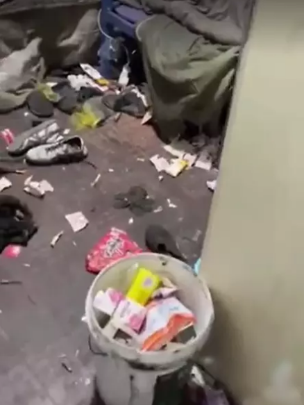 Cảnh tượng bên trong căn phòng là rác rưởi ngập như núi, bày bừa từ ngoài cửa vào trong, chăn chiếu ngả màu, quần áo vứt linh tinh từ giường xuống nền nhà.