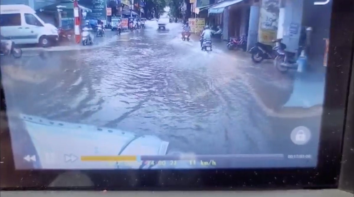 Theo clip, con phố nhỏ ngập nước sau mưa lớn, nhiều ô tô và xe máy di chuyển chậm để tránh bị ướt. Bỗng từ phía sau một chiếc xe bán tải vượt qua chiếc xe taxi, tăng ga đi nhanh tạt nước vào hai bên, lên cả người đi đường.