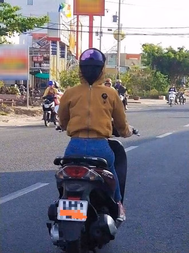 Hình ảnh một người phụ nữ mặc áo và đội mũ ngược, kiểu trang phục chống nắng bá đạo này khiến người đi đường khó hiểu làm thế nào để nhìn được đường mà di chuyển.