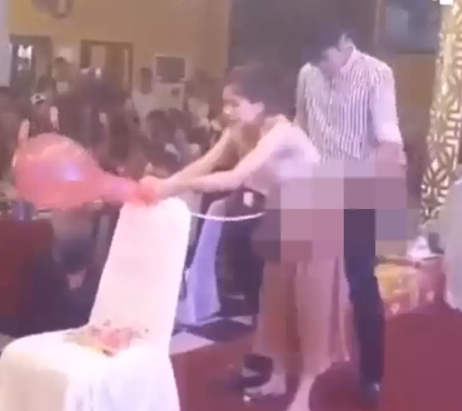 Trong clip một đôi nam nữ đang tham gia trò chơi bơm bóng bay, thay vì kết hợp với nhau bơm theo cách thức thông thường, hai người này lại thoải mái thực hiện trong tư thế vô cùng phản cảm. Ảnh: Chụp màn hình