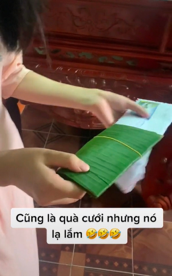 Đoạn video này đã ghi lại cảnh cô dâu đang bóc chiếc phong bì quà mừng cưới của bạn thân. Nhìn bên ngoài chiếc phong bì có vẻ rất dày nhưng bên trong lại toàn là lá chuối. Ảnh: Cắt từ clip TikTok V.J