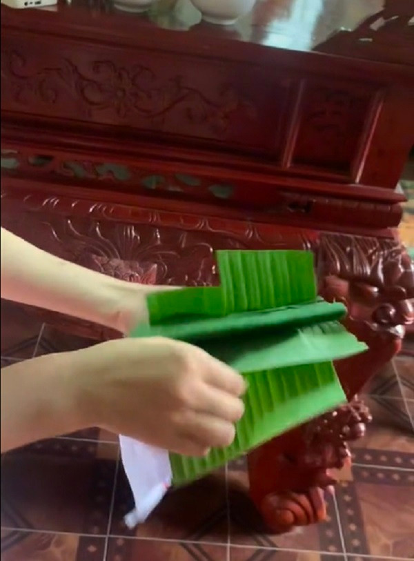 Cô dâu kiên nhẫn bóc từng lượt lá chuối ra. Sau một hồi tháo chun buộc, bóc lá chuối cuối cùng cũng thấy một phong bao lì xì màu đỏ. Ảnh: Cắt từ clip TikTok V.J