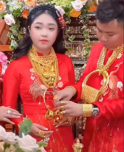 Cụ thể, trong đám cưới toàn vàng này, cả cô dâu và chú rể đều được đeo kiềng vàng, lắc tay vàng nặng trĩu. Thậm chí, vì số vàng nhiều quá mà họ còn phải xâu thành chuỗi mới hết. Ảnh: Cắt từ clip TikTok N.V