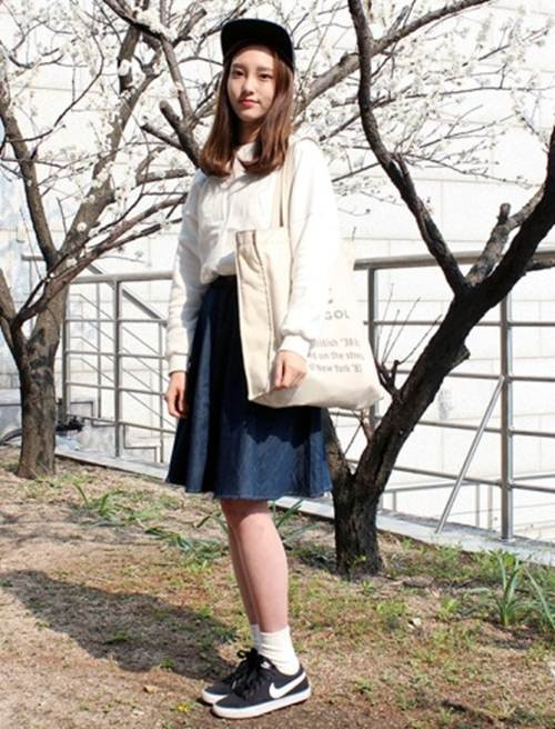 Cô bạn này lựa chọn phong cách nữ tính nhưng không kém phần khỏe khoắn với áo sơ mi, váy denim chữ A, giầy thể thao ăn dơ cùng mũ snapback, cuối cùng không thể thiếu chiếc túi vải oversize để hoàn thiện trang phục.