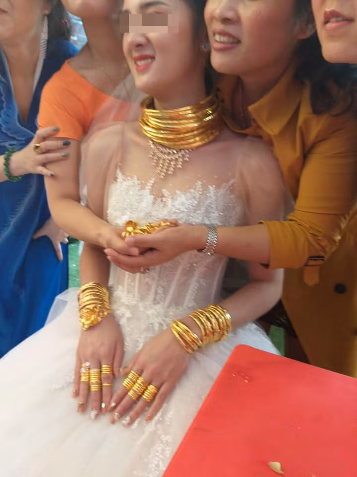 Mới đây, những hình ảnh một cô dâu đeo vàng kín người từ cổ đến tay khiến cộng đồng mạng trầm trồ. Cặp đôi được tặng nhiều vàng đến nỗi cô dâu không đeo hết, người thân xung quanh phải cầm hộ.