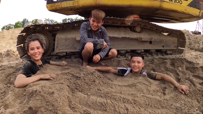 Cụ thể, trong clip lần này con trai bà Tân Vlog đào sẵn 2 hố cát to. Sau đó dùng tiền để dụ dỗ 2 người em nhảy xuống lấy và cuối cùng dùng cát vùi lên trên.