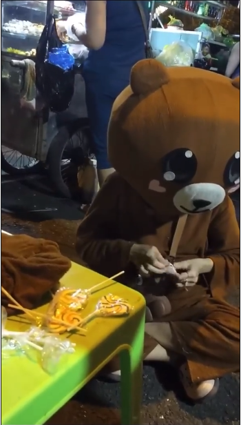 Theo yêu cầu của khách, cô gái bán kẹo ngồi và ăn từng que kẹo trước sự chứng kiến và quay clip của 2 thanh niên. Đến que thứ 7, cô gái bật khóc.