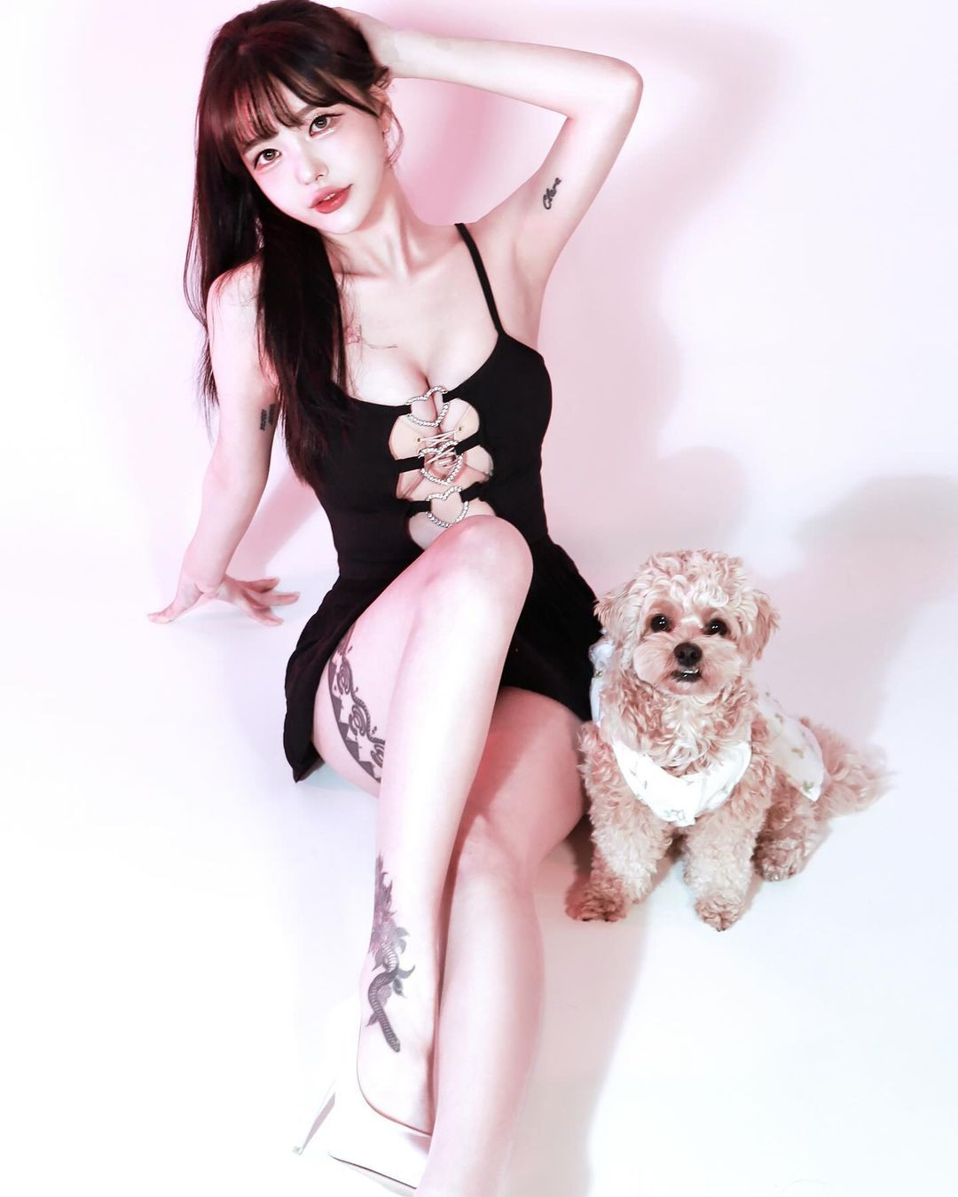 Cô nàng chụp hình cũng chú cún cưng trong trang phục cắt xẻ màu đen bí ẩn, cách điệu với phần ngực là những khoen cài hình trái tim khoe trọn vòng 1 đẫy đà.