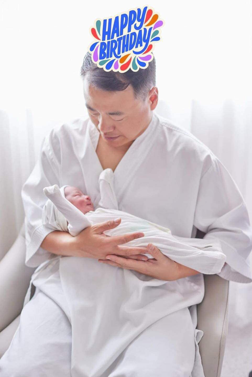 Shark Bình ôm con một cách vụng về nhưng cẩn thận, nhìn con đầy yêu thương.