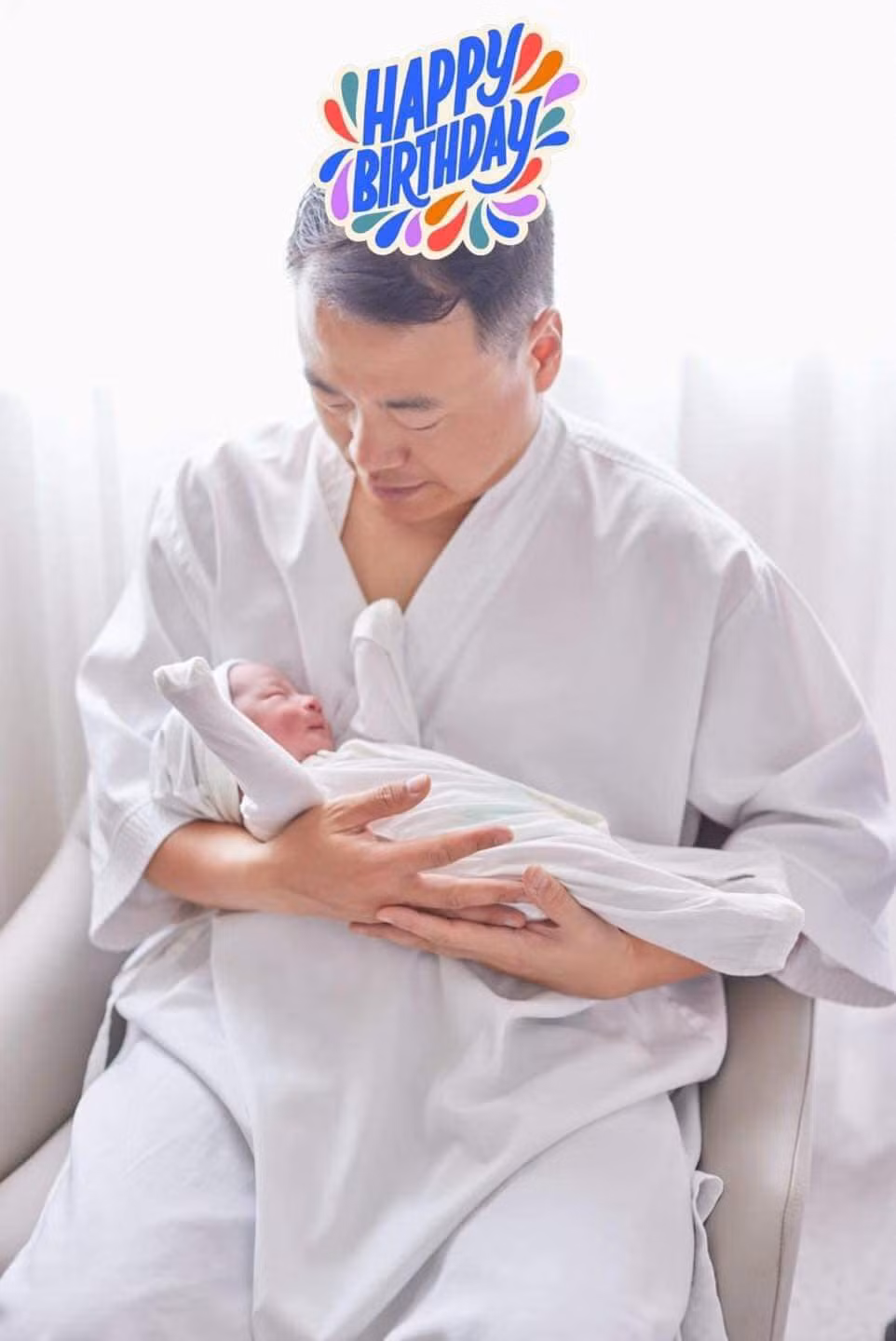 Shark Bình ôm con một cách vụng về nhưng cẩn thận, nhìn con đầy yêu thương.