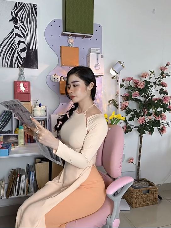 Chiếc áo dài cổ yếm màu cam ôm sát khoe trọn đường cong cơ thể.