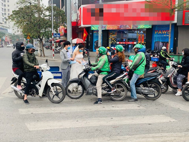 Theo đó, chú rể mặc vest và đeo tấm biển "Khẩu trang miễn phí" trước ngực, đồng thời cùng cô dâu vẫn mặc váy cưới đứng tại ngã tư Xã Đàn - Phạm Ngọc Thạch phát cho người đi đường. Hành động đẹp giữa đại dịch corona của cặp đôi ngay lập tức được cộng đồng mạng tán dương.
