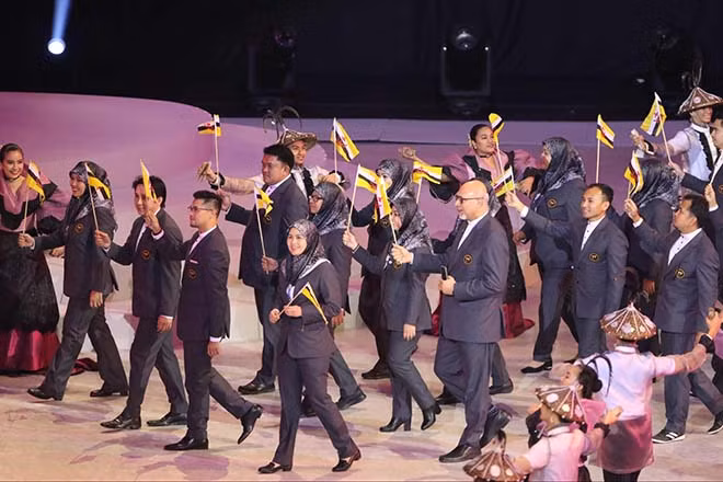 Xuất hiện đầu tiên tại SEA Games 30 là đoàn thể thao Brunei với trang phục vest đen lịch lãm, phụ nữ có thêm khăn trùm đầu tối màu.