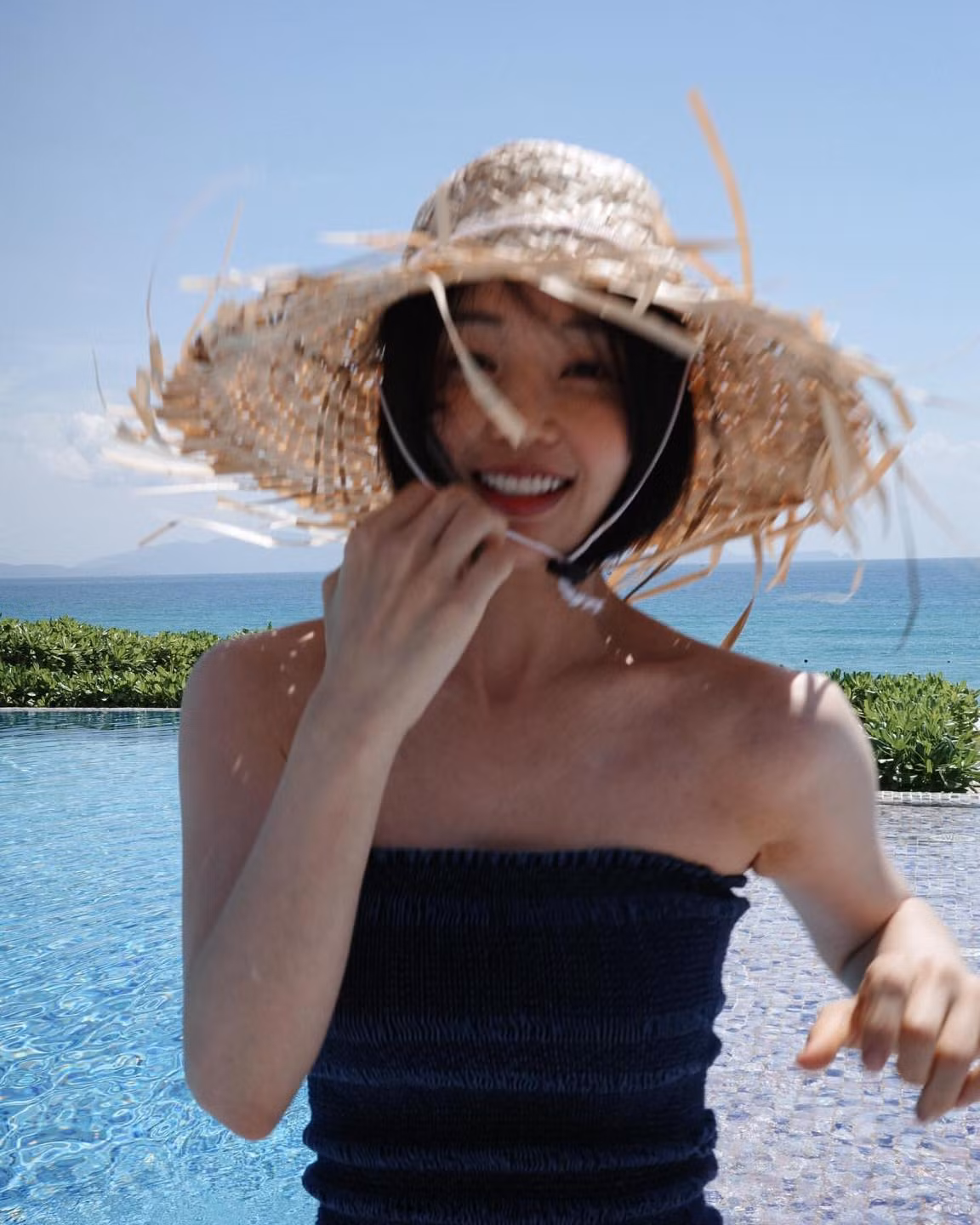 Cô nàng chụp ảnh tại một hồ bơi của resort ngay cạnh bờ biển. Mỹ nhân màn ảnh Hàn diện chiếc áo quây tối màu đơn giản, mang chiếc mũ lá cọ đặc trưng của những khu du lịch biển ở Việt Nam.