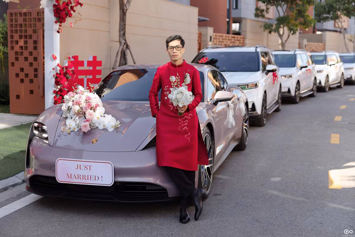 Chú rể trong trang phục áo dài đỏ đứng trước dàn xe nhà trai.