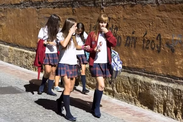 Học sinh tại cộng đồng tự trị Castilla và León, Tây Bắc Tây Ban Nha, trông thời trang trong bộ đồng phục thống gồm tất dài màu đen, váy kẻ xếp ly, áo thun trắng và áo khoác mỏng gắn logo trường.