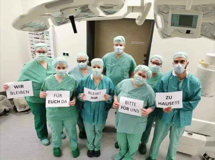 Nhóm bác sĩ người Đức giơ cao câu khẩu hiệu bằng tiếng địa phương để tuyên truyền tránh dịch Covid-19.