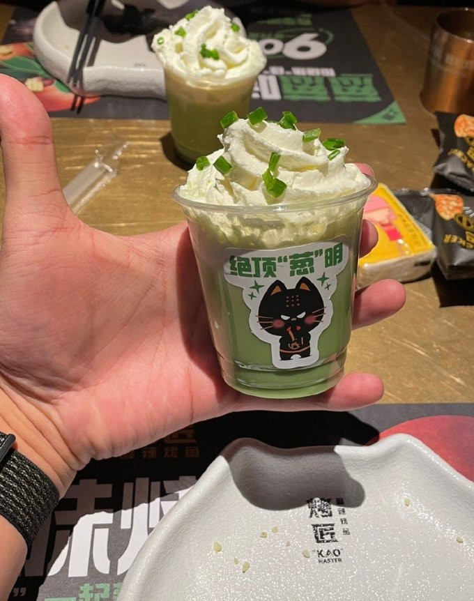 Thức uống do một tiệm cá nướng nghĩ ra. Theo đó, thực khách ghé quán ăn cá nướng trong 1 khoảng thời gian nhất định sẽ được mua trà sữa hành lá cỡ nhỏ (mini) với giá 6,6 NDT (khoảng 22.000 đồng) một ly.