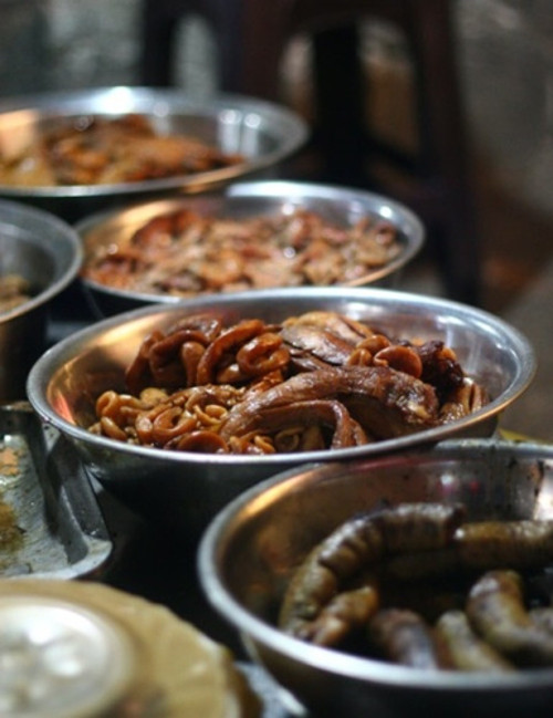  Lòng nướng Gầm Cầu. Dù phải ngồi dưới chân cầu, thi thoảng lại có tiếng tàu xình xịch chạy qua, nhưng các dãy quán ở đây vẫn rất hút khách. Các món được phục vụ ở đây khá đa dạng: từ nầm – bò – dạ dày- lòng – thịt ba chỉ… Giờ cao điểm của phố lòng nướng là tầm 20h. Giá ở đây chỉ từ 35.000-50.000 đồng/đĩa.