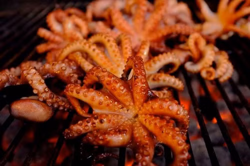 Mực nướng Hàng Bồ. Những quán mực nướng trên con phố này chỉ hoạt động nhộn nhịp vào khoảng 21h-22h trở đi. Một cái bếp than hoa nhỏ, một mẹt mực khô cùng vài chiếc chiếu, thế là bất cứ nơi đâu trên con phố này đã có thể mọc lên một tiệm mực nướng.