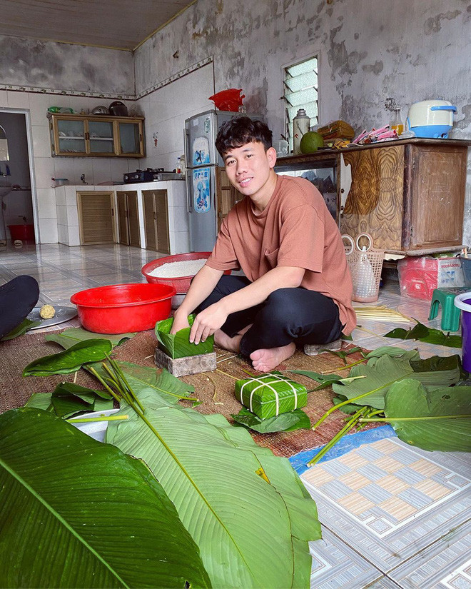 Minh Vương hí hửng ngồi gói bánh chưng cùng mẹ khi trở về quê. Anh chàng có vẻ vô cùng thích thú với công việc này. Năm nay đón Tết, cầu thủ của CLB Hoàng Anh Gia Lai làm mái tóc xoăn đen bồng bềnh có phần giống với đồng đội Văn Toàn.