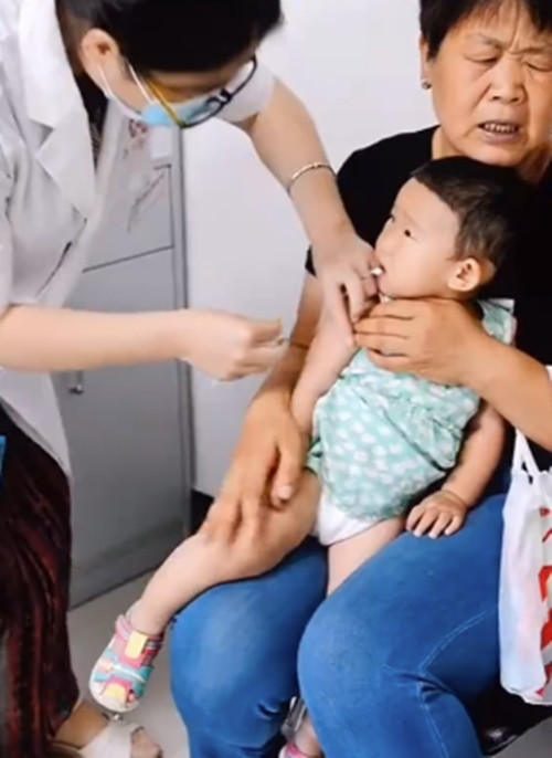 Em bé cùng bà đi tiêm, ban đầu thì em bé nhìn cô ý tá vẻ tò mò.