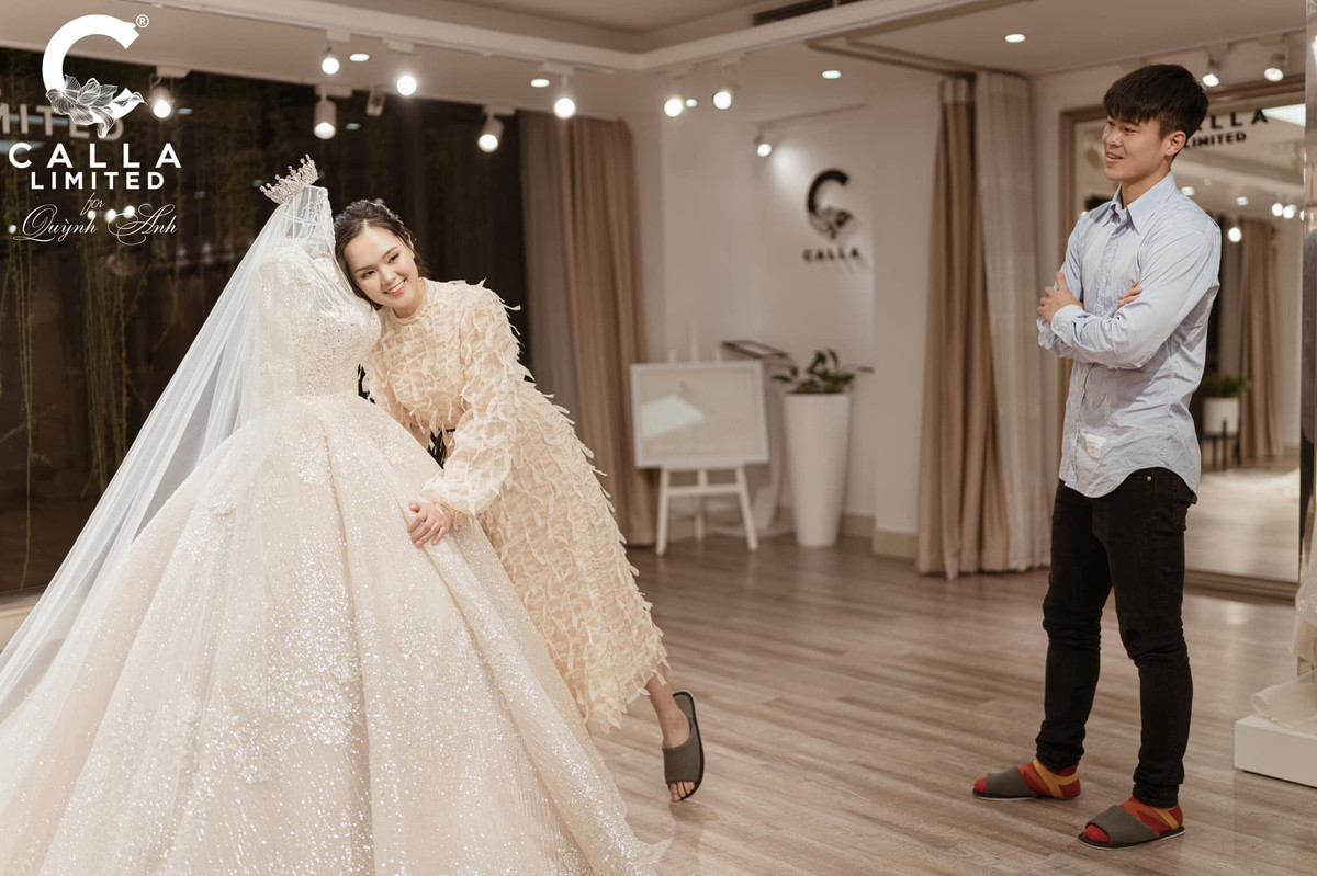 Duy Mạnh hạnh phúc nhìn vợ bên cạnh chiếc váy cưới sẽ được mặc trong ngày trọng đại.