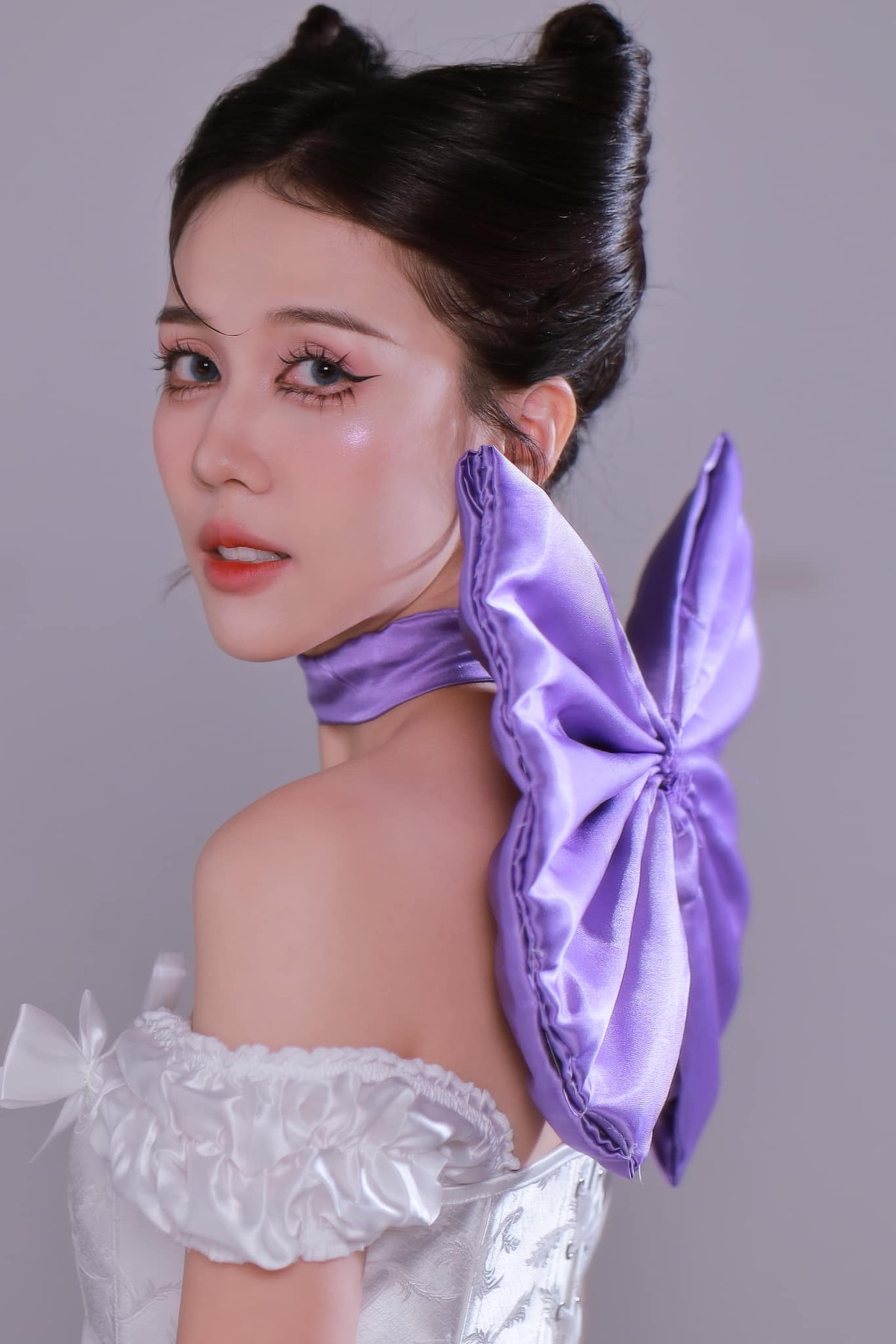 Đoạn video khởi động bằng gương mặt mộc đang skincare, chỉ cần một cái quay mặt là biến thành cô mèo xinh đẹp, đỏng đảnh, kiêu kì. Điểm nhấn của phần trang điểm chính là đôi mắt to tròn long lanh, cùng phục trang gôm chiếc nơ màu tím lớn phía sau cổ.