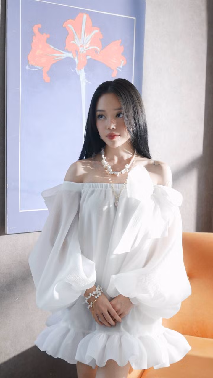 Với thiết kế váy màu trắng phồng ở phần ống tay, kết hợp cùng một số phụ kiện cùng tone như vòng tay và dây chuyền, Linh Ngọc Đàm tựa như một nàng công chúa đoan trang, hiền dịu.