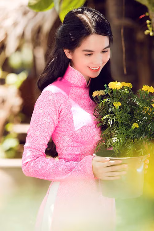 Ngọc Trinh e ấp bên hoa cúc vàng.