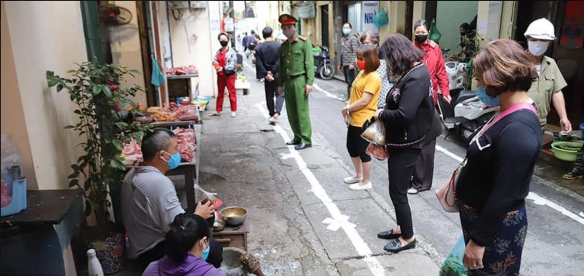 Tất cả mọi người khi tới mua hàng tại khu chợ dân sinh đều đứng nghiêm chỉnh tại vạch đã được kẻ sẵn để giữ an toàn trước khả năng lây lan COVID-19. Đặc biệt, 100% người có mặt tại chợ đều sử dụng khẩu trang.