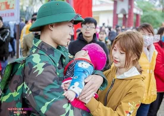 Chàng chiến sĩ trẻ tranh thủ ôm con nhỏ trước khi cùng đồng đội lên đường vào đơn vị. Em bé còn quá nhỏ, không nhận thức được sự vắng mặt của bố trong vài năm sắp tới.